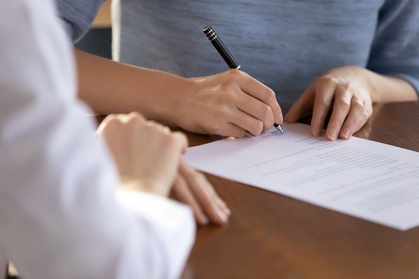 Last formality. Close up of young woman job applicant being hired on vacant place signing employment contract in presence of recruiter, female bank client putting signature under financial document