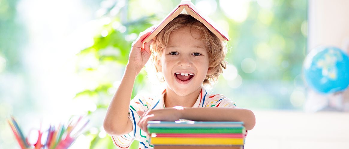 Kinder gehen wieder zur Schule. Kinder lernen und studieren für die Vorschule. Kleiner Junge der Grundschule macht Hausaufgaben. Schlafzimmer mit Schreibtisch, Büchern und Globus für Kleinkind. Kind lernt lesen und schreiben.
