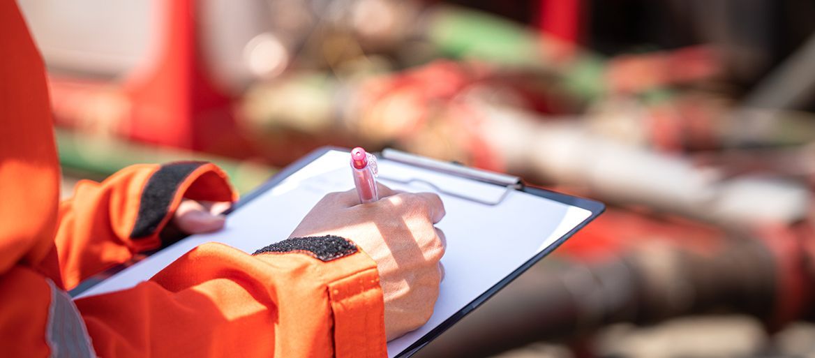 Foto: shutterstock Sicherheitsbeauftragter oder Vorgesetzter macht sich während der Durchführung von Audits und Inspektionen im Ölfeldbetrieb Notizen auf dem Checklistenpapier. Nahaufnahme und selektives Fokusfoto.